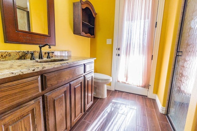 bathroom with wood tiled floor, baseboards, vanity, and toilet