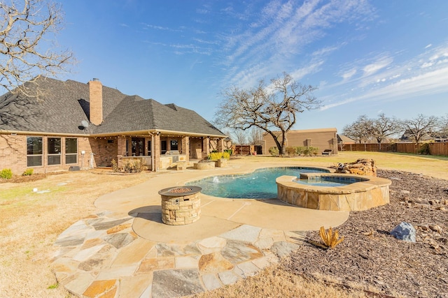 view of pool featuring a fire pit, a patio, fence, and a pool with connected hot tub