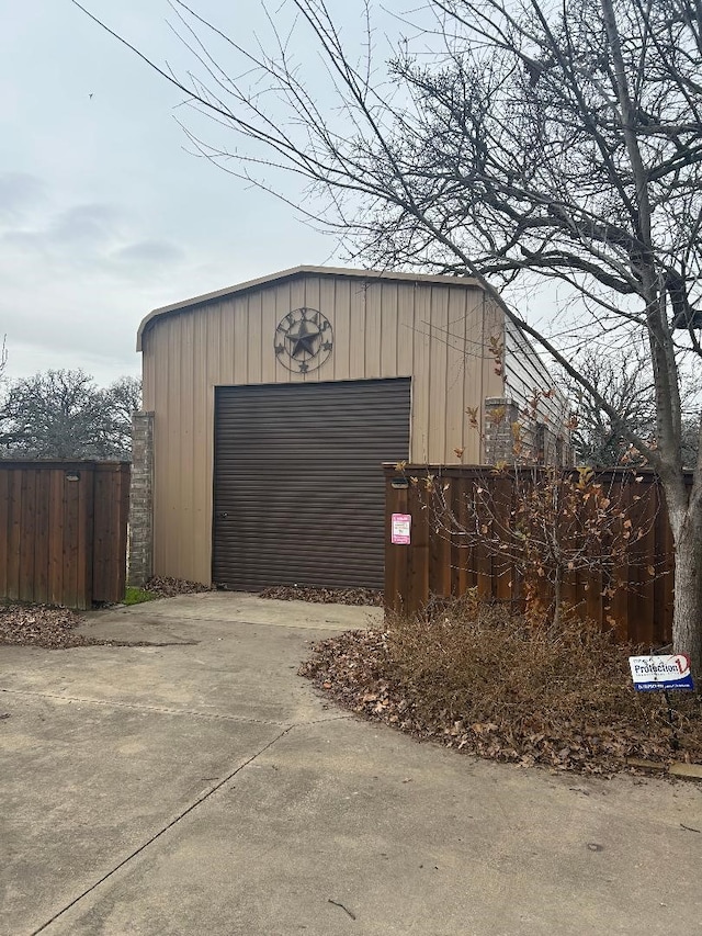 detached garage featuring fence and driveway