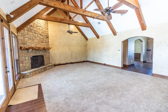 unfurnished living room with a fireplace, dark carpet, and beam ceiling