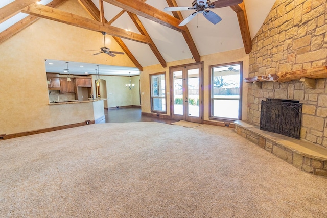 unfurnished living room with dark carpet, beamed ceiling, french doors, a fireplace, and high vaulted ceiling