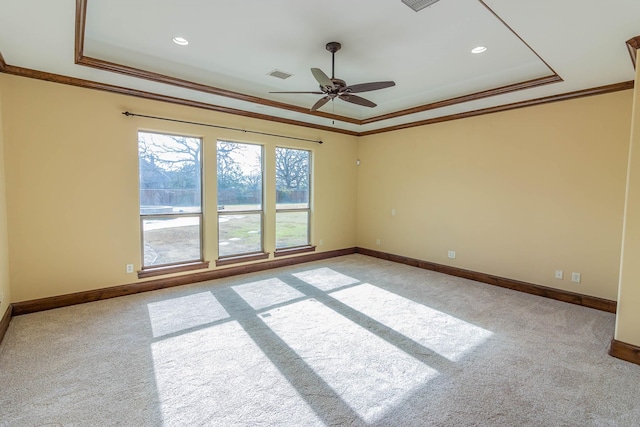 spare room featuring light carpet, visible vents, baseboards, ornamental molding, and a raised ceiling