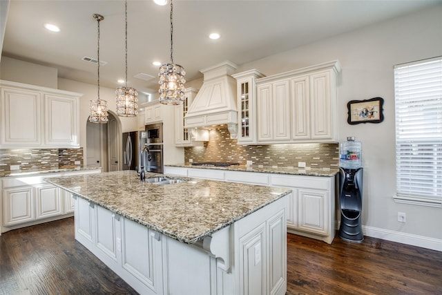 kitchen featuring premium range hood, white cabinetry, and a kitchen island with sink