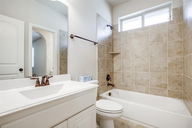 full bathroom featuring vanity, tiled shower / bath combo, and toilet