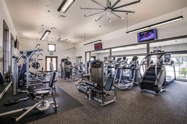 workout area featuring a high ceiling, ceiling fan, and a healthy amount of sunlight