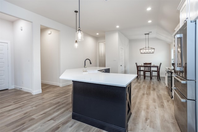 kitchen featuring hanging light fixtures, high end refrigerator, a kitchen island with sink, and lofted ceiling