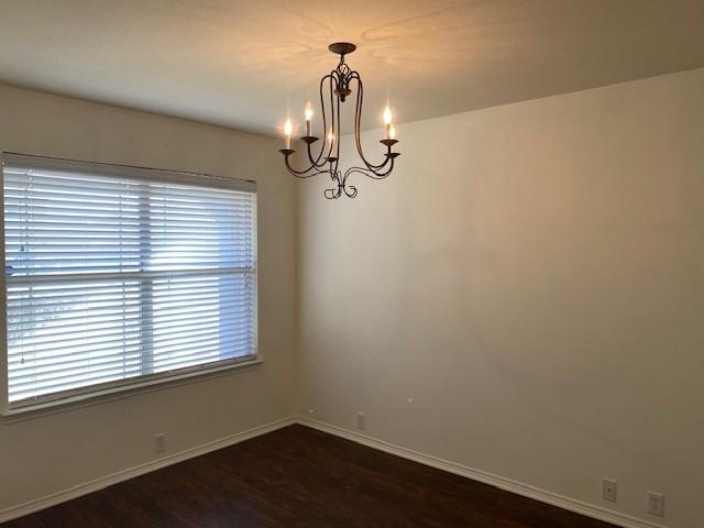 empty room featuring dark hardwood / wood-style floors and an inviting chandelier