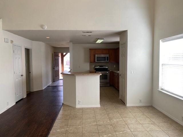 kitchen featuring light tile patterned floors, kitchen peninsula, and appliances with stainless steel finishes