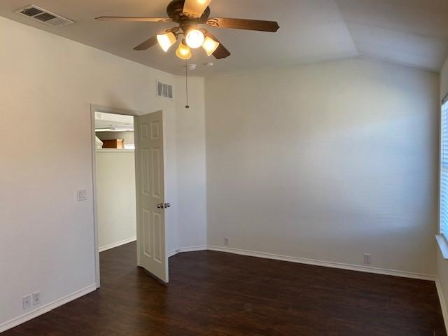 unfurnished room featuring ceiling fan, dark hardwood / wood-style floors, and vaulted ceiling