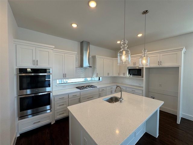 kitchen with white cabinets, appliances with stainless steel finishes, wall chimney exhaust hood, and sink