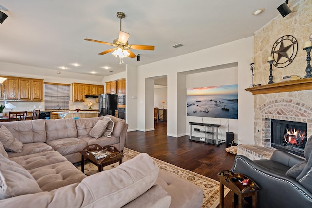 living room with ceiling fan, dark hardwood / wood-style flooring, sink, and a brick fireplace