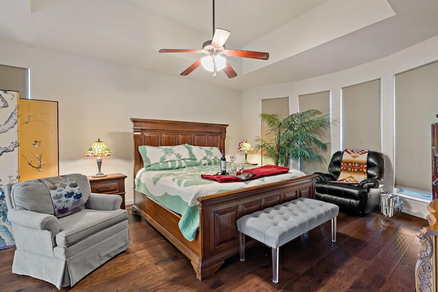 bedroom with a raised ceiling, ceiling fan, and dark wood-type flooring