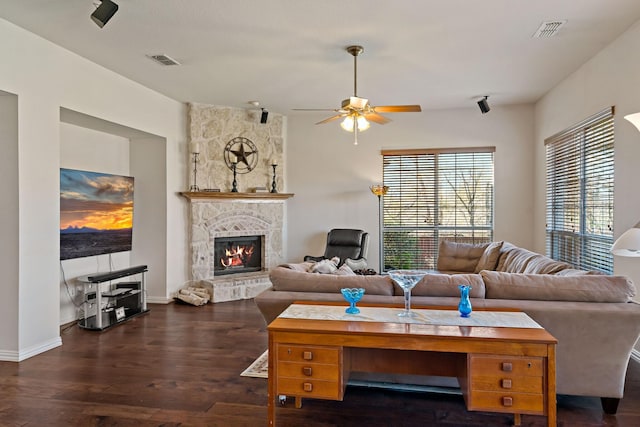 living room featuring ceiling fan, a fireplace, and dark wood-type flooring