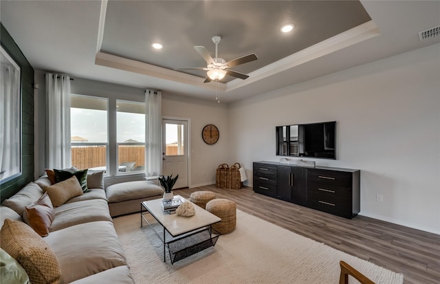 living room featuring a tray ceiling, ceiling fan, and light hardwood / wood-style floors