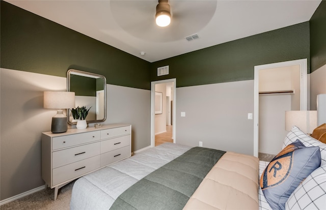 bedroom with a closet, light colored carpet, a spacious closet, and ceiling fan