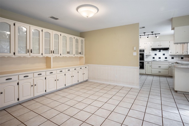 kitchen featuring backsplash, white cabinetry, double wall oven, and light tile patterned floors