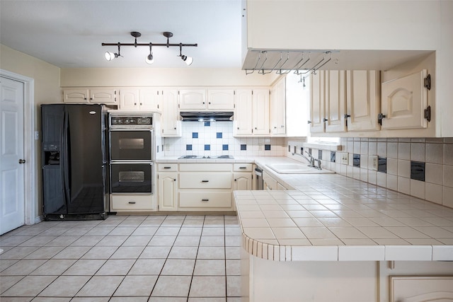 kitchen featuring kitchen peninsula, decorative backsplash, sink, black appliances, and tile counters