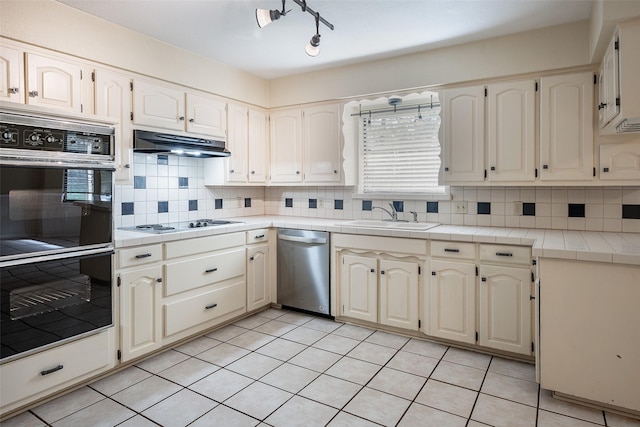 kitchen featuring sink, tasteful backsplash, stainless steel dishwasher, tile countertops, and black double oven