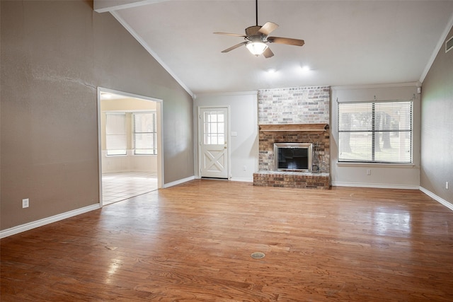 unfurnished living room featuring ceiling fan, a brick fireplace, hardwood / wood-style floors, lofted ceiling, and ornamental molding