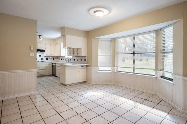 kitchen featuring kitchen peninsula, tasteful backsplash, stainless steel dishwasher, and light tile patterned flooring