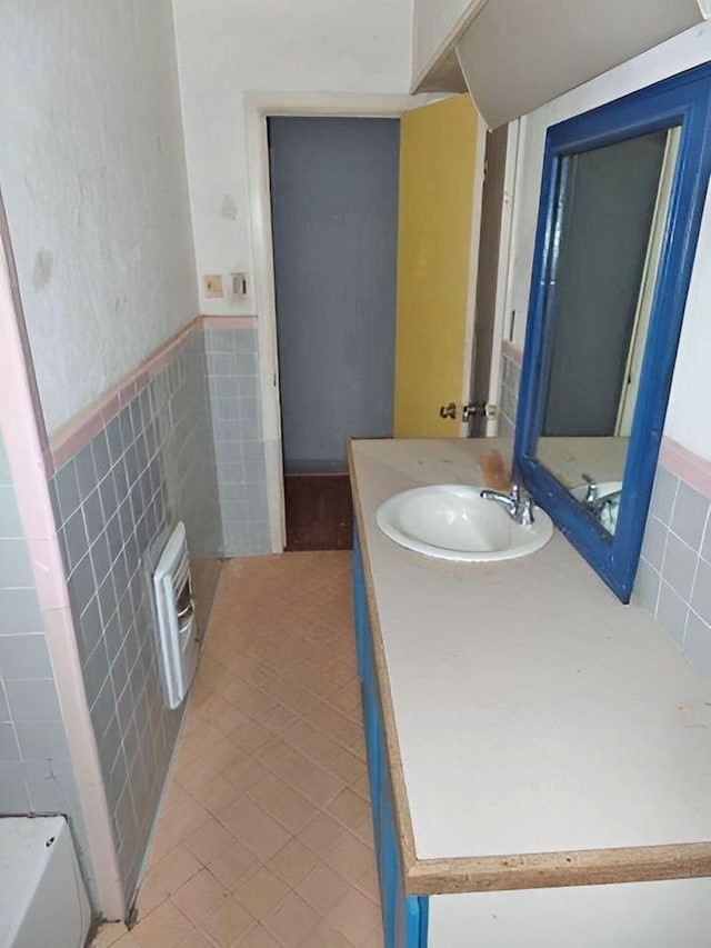 bathroom featuring tile patterned floors, vanity, a bathtub, and tile walls