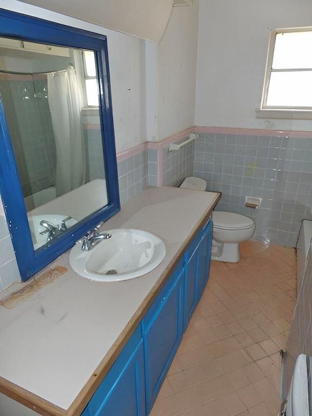 bathroom featuring walk in shower, tile patterned floors, toilet, vanity, and tile walls