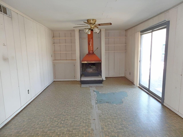 unfurnished living room with ceiling fan and wooden walls