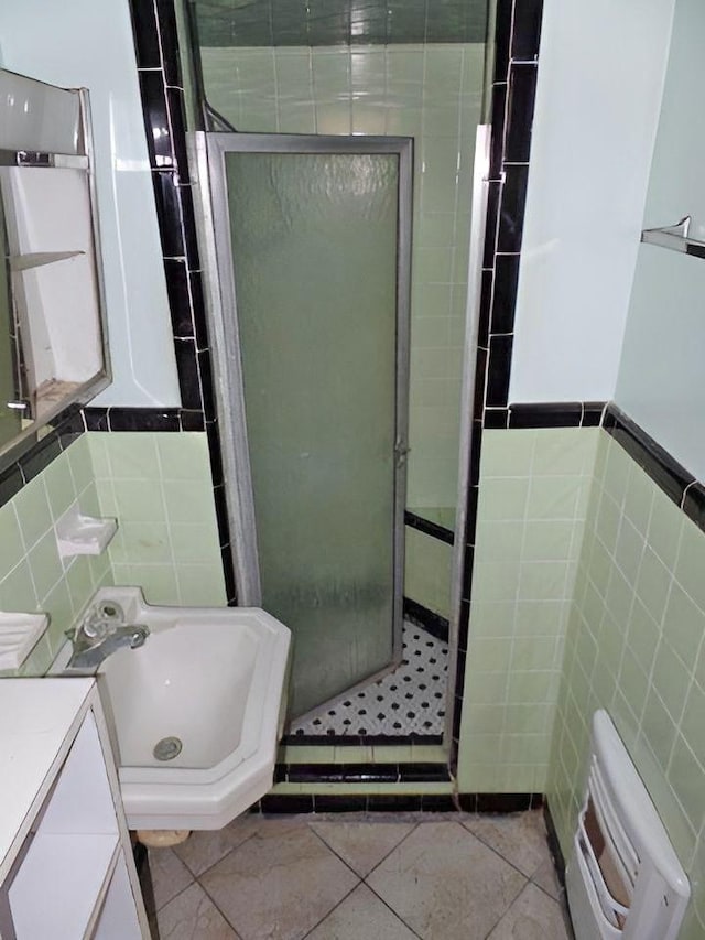 bathroom with vanity, tile patterned floors, tile walls, and a shower with shower door