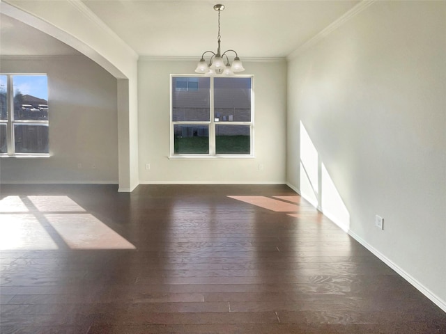 spare room featuring dark wood-type flooring, crown molding, and a chandelier