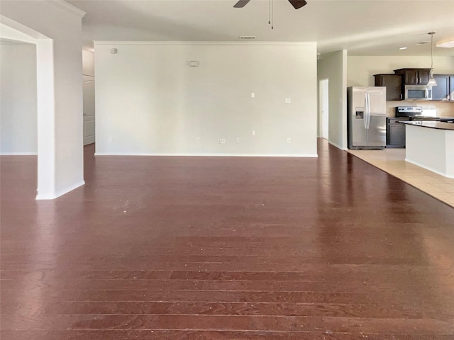 unfurnished living room featuring dark wood-type flooring, ceiling fan, and ornamental molding