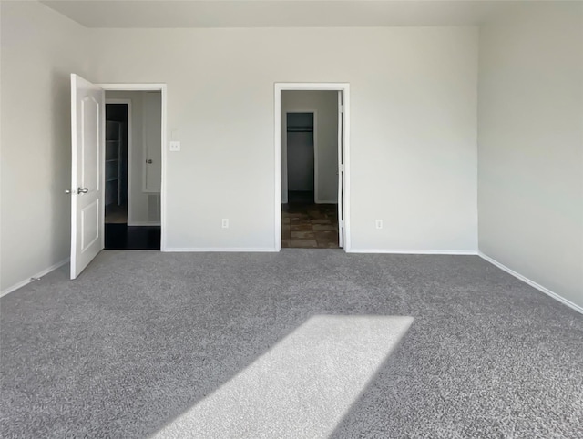 unfurnished bedroom with dark colored carpet and a spacious closet