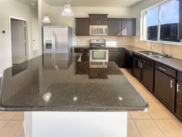 kitchen featuring stainless steel appliances, a center island, sink, and dark stone countertops