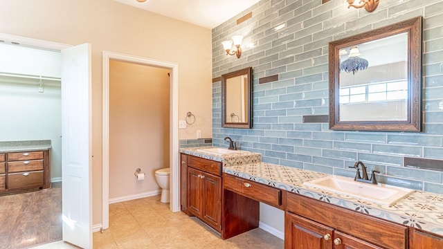 bathroom featuring vanity, toilet, and backsplash