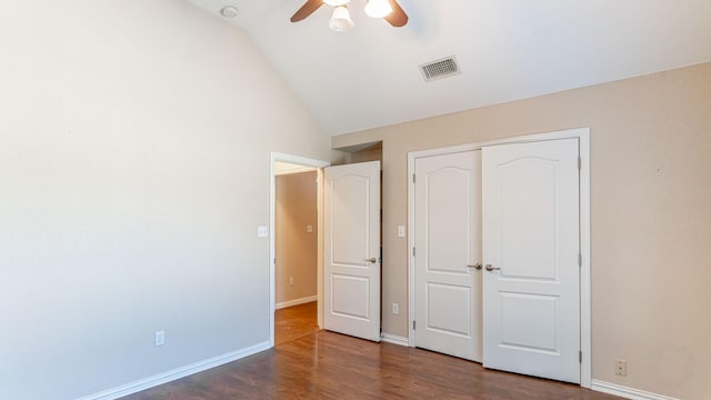 unfurnished bedroom featuring a closet, ceiling fan, dark hardwood / wood-style flooring, and vaulted ceiling