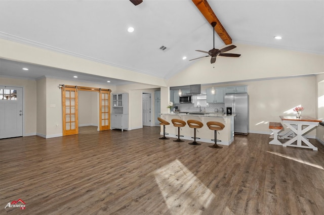 kitchen featuring backsplash, lofted ceiling with beams, gray cabinets, appliances with stainless steel finishes, and a breakfast bar area