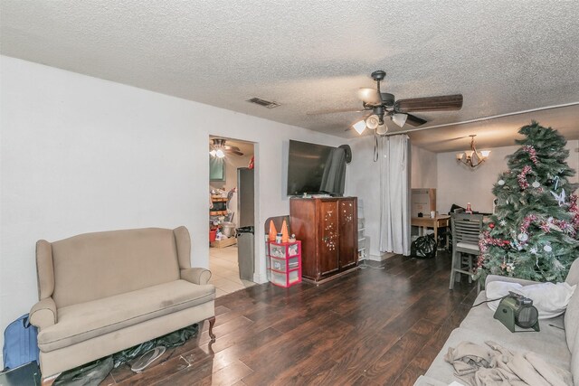 living room with hardwood / wood-style flooring, ceiling fan with notable chandelier, and a textured ceiling