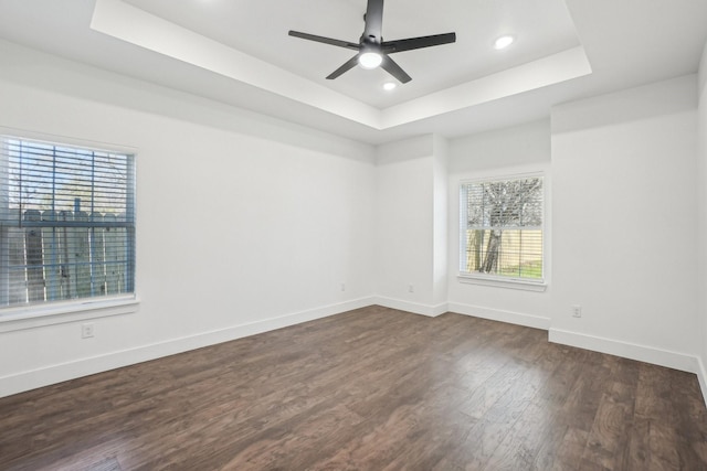 unfurnished room featuring a tray ceiling, dark hardwood / wood-style floors, and ceiling fan