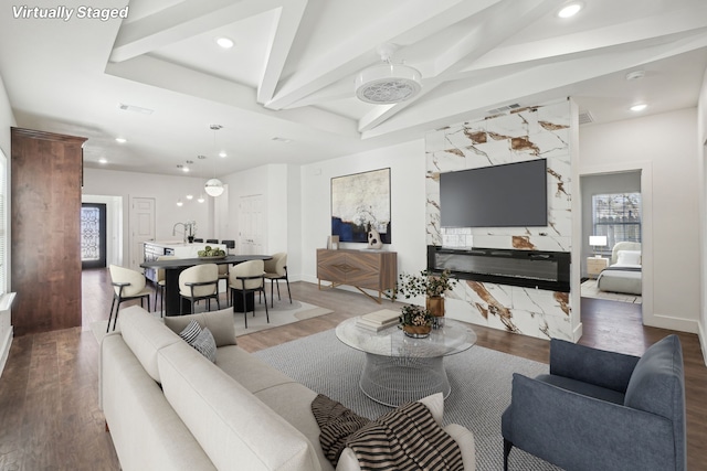 living room with hardwood / wood-style floors, a high end fireplace, lofted ceiling with beams, and sink