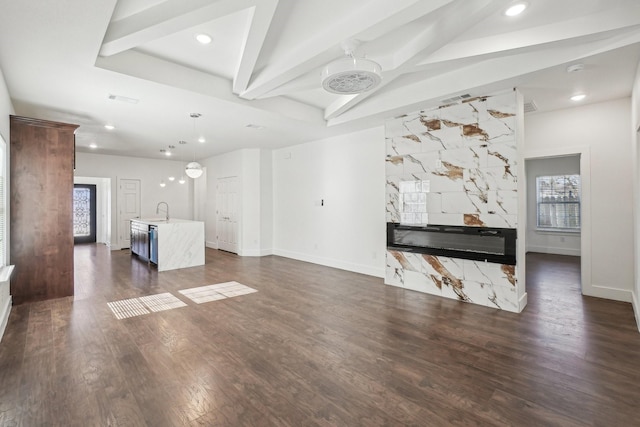 unfurnished living room with dark wood-type flooring, sink, and lofted ceiling with beams