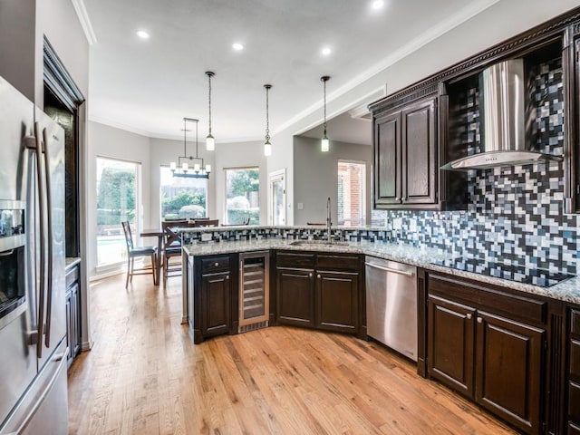 kitchen with appliances with stainless steel finishes, backsplash, beverage cooler, sink, and decorative light fixtures