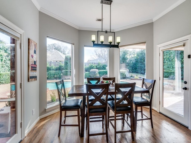 dining area with an inviting chandelier, crown molding, and hardwood / wood-style flooring