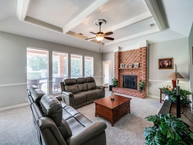 living room featuring light carpet, a tray ceiling, ceiling fan, crown molding, and a fireplace