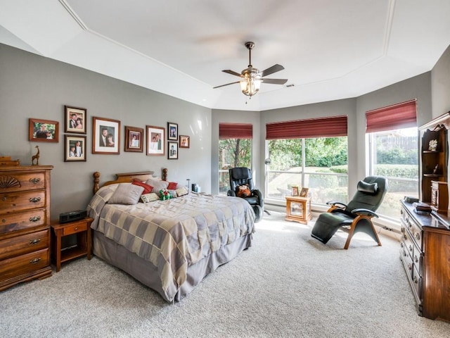 carpeted bedroom with a raised ceiling, ceiling fan, and multiple windows