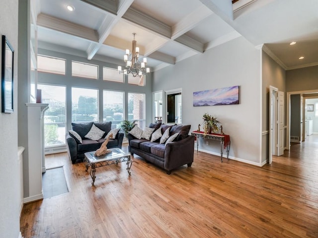 living room with coffered ceiling, beamed ceiling, a chandelier, hardwood / wood-style flooring, and a high ceiling