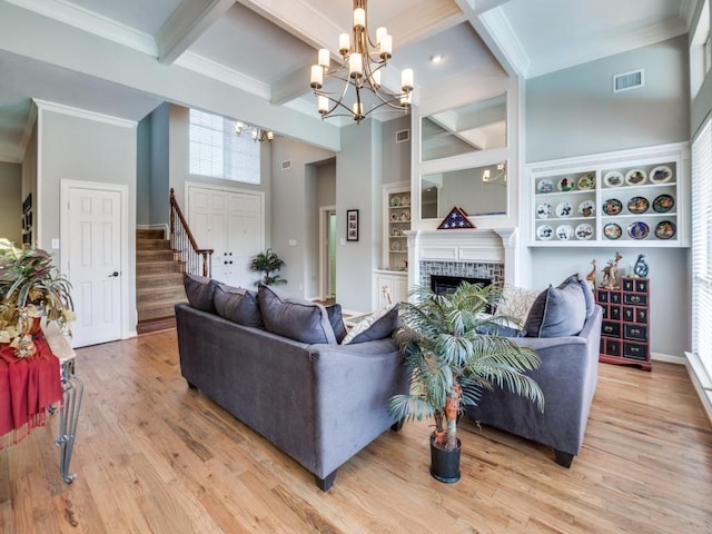 living room featuring crown molding, beam ceiling, a notable chandelier, a fireplace, and hardwood / wood-style floors