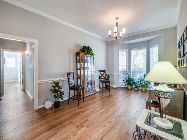 living area featuring an inviting chandelier, ornamental molding, wood-type flooring, and a wealth of natural light