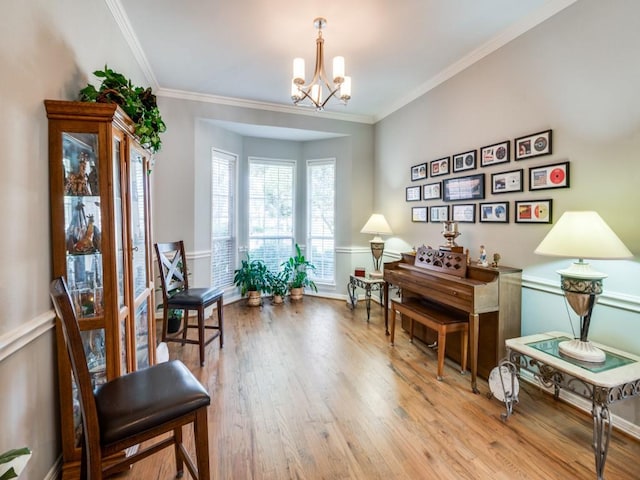 living area with a notable chandelier, light wood-type flooring, and ornamental molding