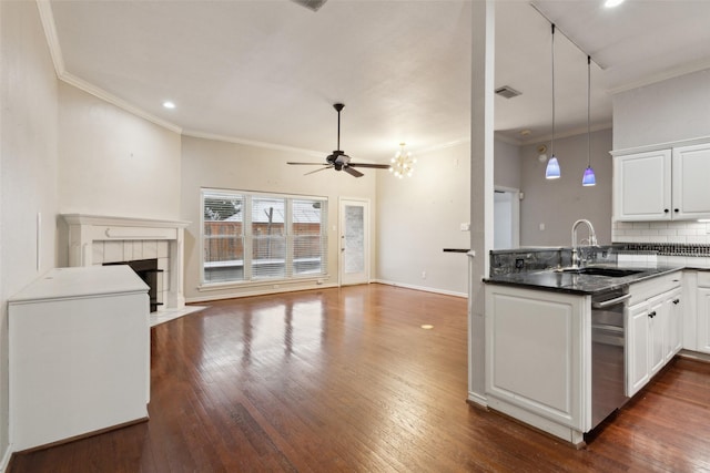 kitchen featuring hanging light fixtures, backsplash, white cabinets, a tiled fireplace, and ceiling fan