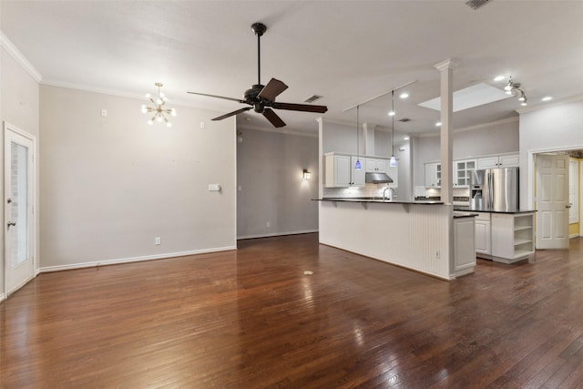 unfurnished living room with ceiling fan with notable chandelier, dark wood-type flooring, and crown molding