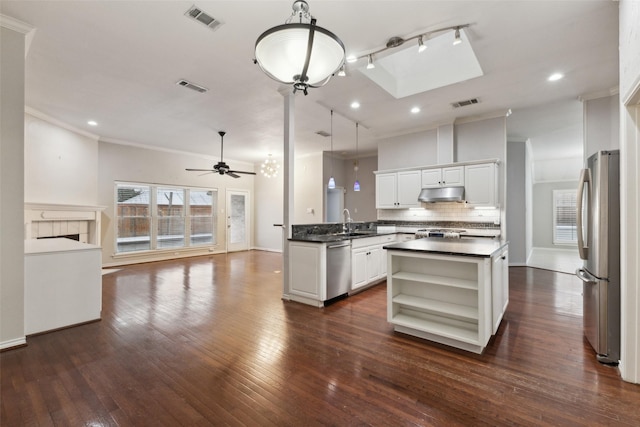 kitchen with tasteful backsplash, white cabinets, hanging light fixtures, and stainless steel appliances